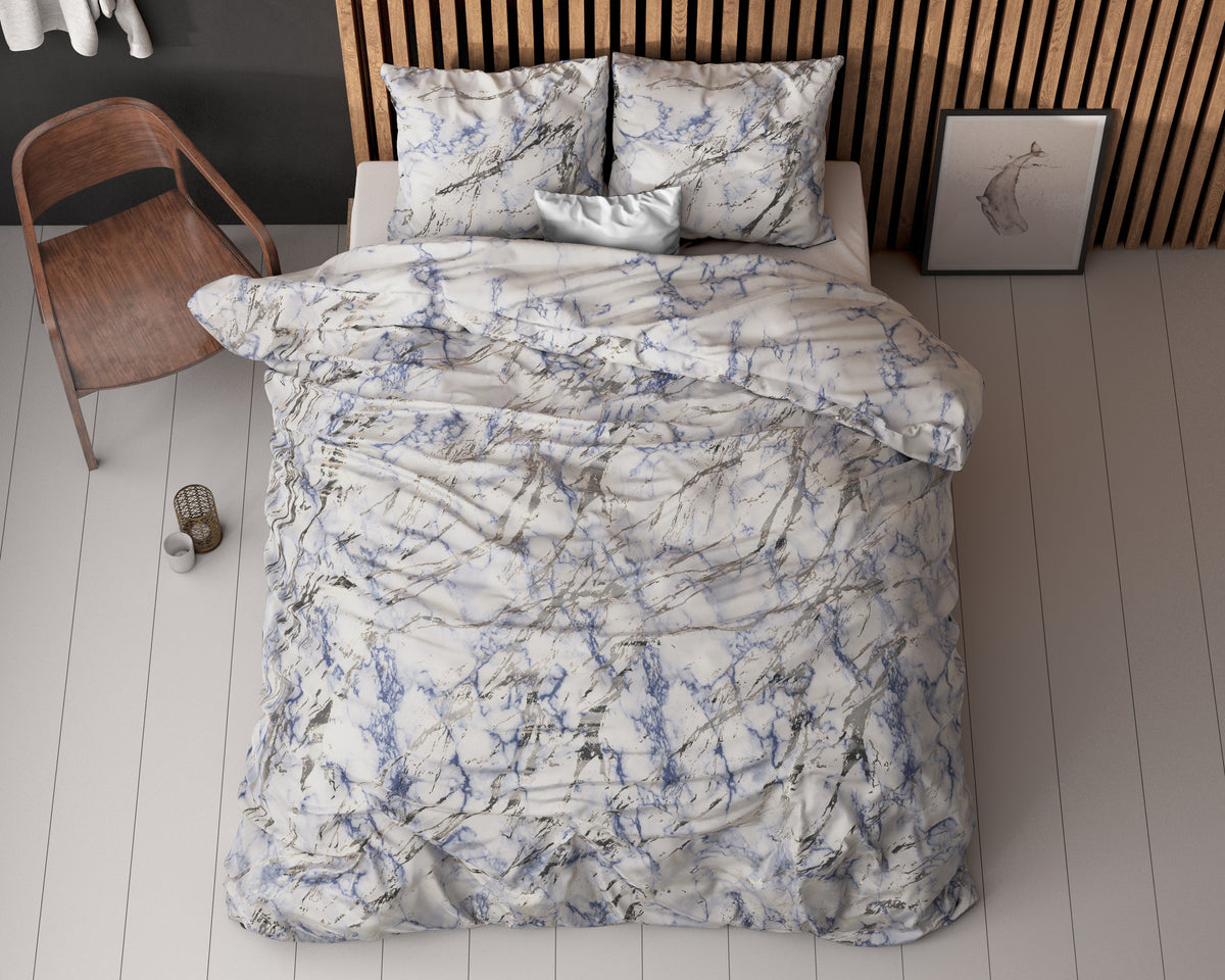 Dekbedovertrek met blauw en grijs marmerpatroon op een bed met bijpassende kussens, gezien van boven