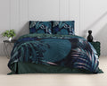 Opgemaakt bed met dekbedovertrek met botanische bladprint in blauw en teal, naast plant en zwarte bijzettafel