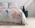 Dekbedovertrek Layla in lichtblauw met roze bloesem en een vogel op een tak, opgemaakt bed met twee kussens
