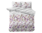 Bed opgemaakt met wit dekbedovertrek met roze en paarse bloemenprint en twee bijpassende kussens