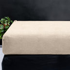 Taupe teddy hoeslaken om een matras, met een groene plant op de achtergrond