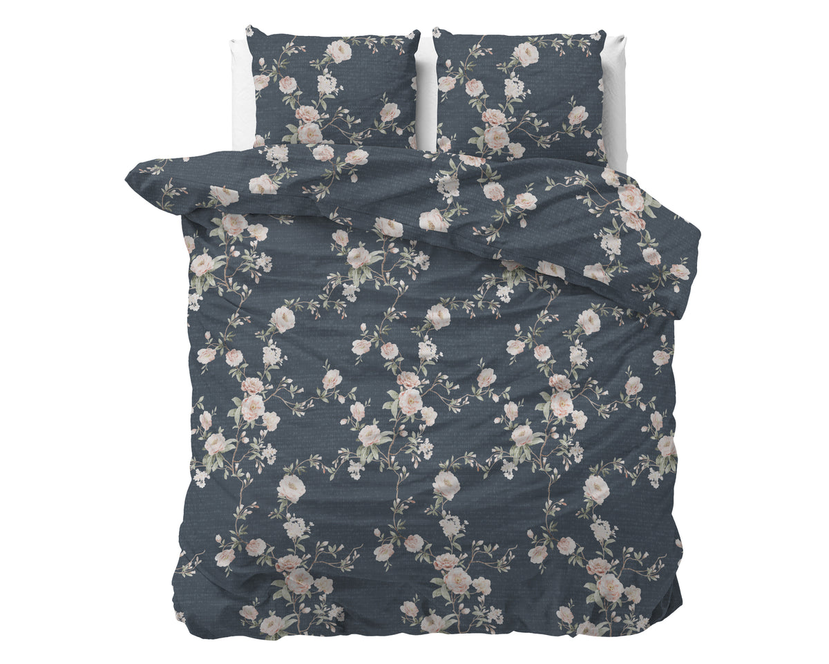 Indigo dekbedovertrek met roze en witte bloemenprint en twee bijpassende kussenslopen op een bed