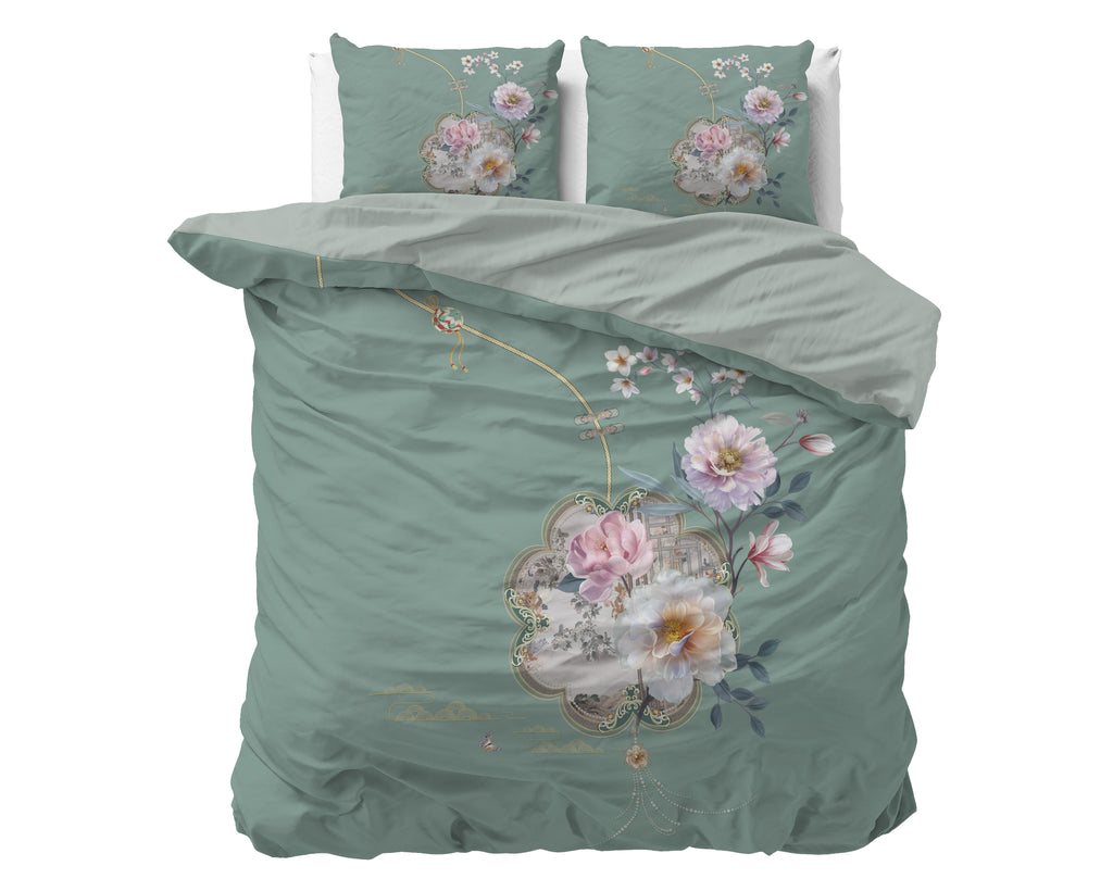 Groen dekbedovertrek Lyra met roze en witte bloemenprint en twee bijpassende kussenslopen op een bed