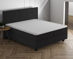 Wit topper op een antracietkleurige boxspring met bijpassend hoofdbord in een lichte slaapkamer met visgraatvloer