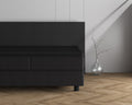 Zwarte topper met hoeslaken op een donkergrijs boxspringbed met hoofdbord, naast een glazen vaas met tak