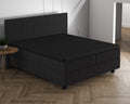 Zwart topperhoeslaken over een topper op een donker boxspringbed met hoofdbord, op een visgraatvloer