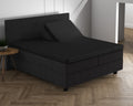 Zwart hoeslaken op een split-topper van een donker boxspringbed, met één helft van de topper omhoog gezet
