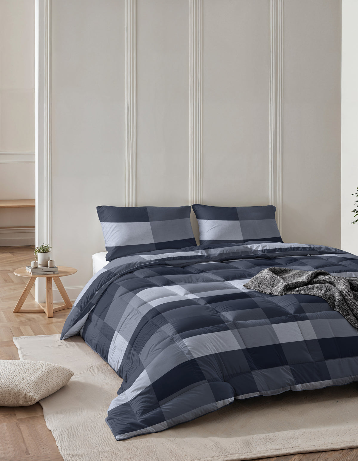 Blauw geblokt lazy dekbed met twee kussens op een bed in een lichte slaapkamer met wandlijsten