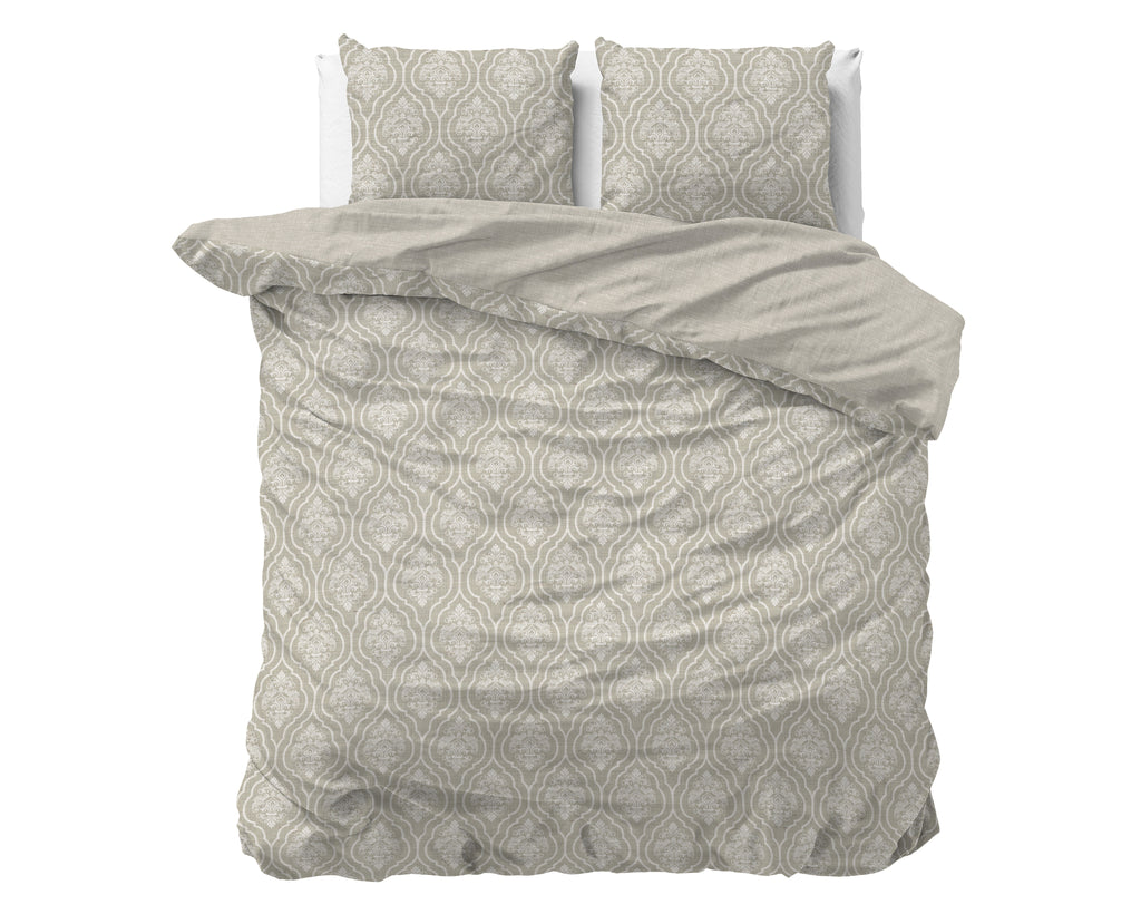 Bed met zandkleurig dekbedovertrek met sierlijk crème dessin en twee bijpassende kussenslopen