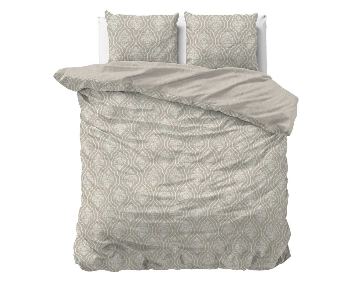 Bed met zandkleurig dekbedovertrek met sierlijk crème dessin en twee bijpassende kussenslopen