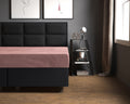 Oudroze velours hoeslaken op een bed met donker gestoffeerd hoofdbord en boxspring in een grijze slaapkamer