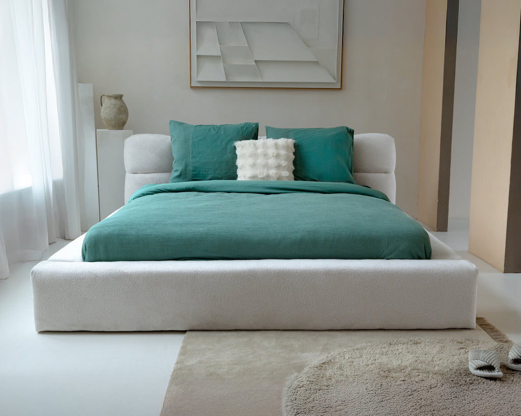 Groen wafel dekbedovertrek met groene kussenslopen op een bed met wit gestoffeerd bedframe in een lichte slaapkamer