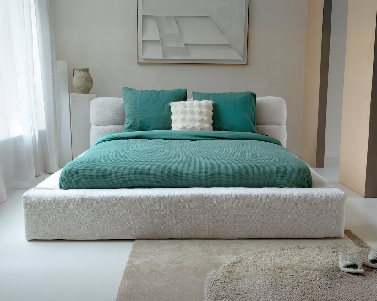 Groen wafel dekbedovertrek met groene kussenslopen op een bed met wit gestoffeerd bedframe in een lichte slaapkamer