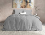 Grijs flanellen dekbedovertrek met grijze kussens op een bed voor een beige muur met schilderij