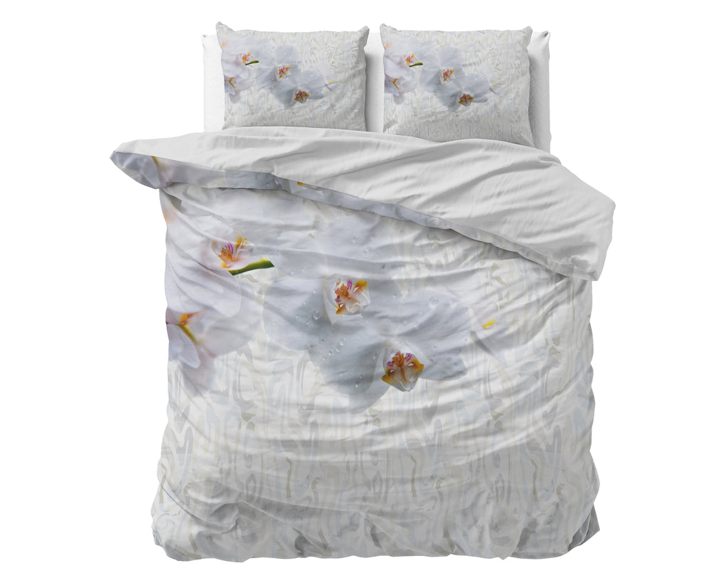 Dekbedovertrek met witte orchideeënprint op een bed, met twee bijpassende kussens