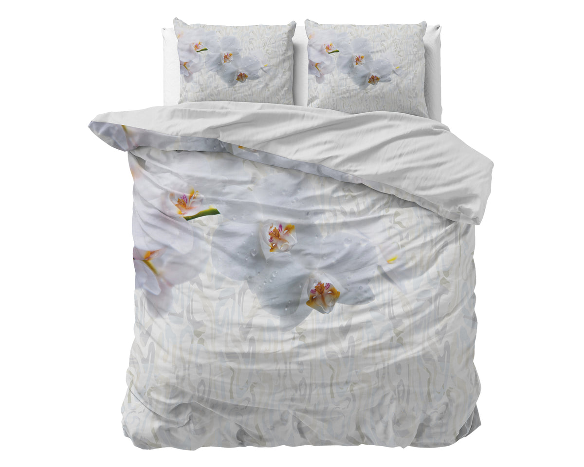 Dekbedovertrek met witte orchideeënprint op een bed, met twee bijpassende kussens