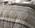 Bed opgemaakt met dekbedovertrek met luipaardprint en grafische motieven in grijs, zwart, creme en goud