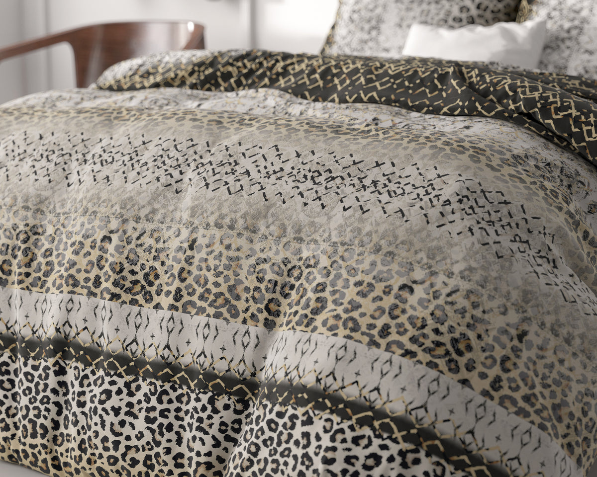 Bed opgemaakt met dekbedovertrek met luipaardprint en grafische motieven in grijs, zwart, creme en goud