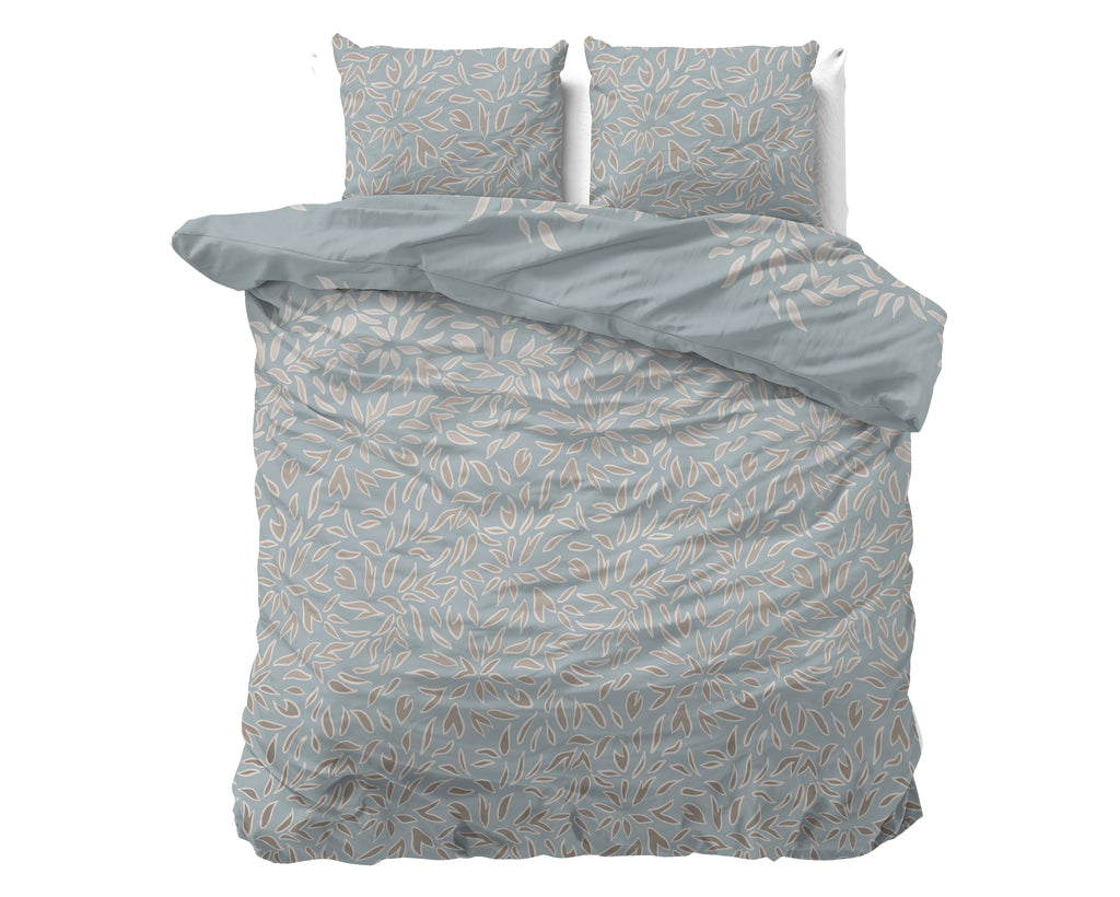 Blauw dekbedovertrek met beige en taupe bladprint, met twee bijpassende kussens op een bed