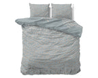 Blauw dekbedovertrek met beige en taupe bladprint, met twee bijpassende kussens op een bed