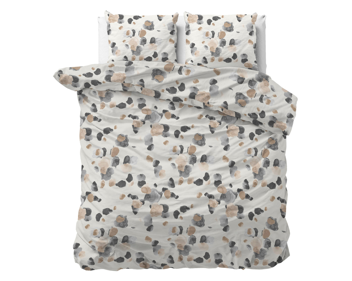 Dekbedovertrek met zandkleurige ondergrond en aquarelstippen in grijs en beige, op bed met twee kussens