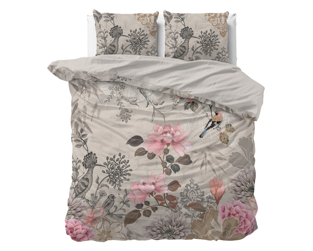 Opgemaakt bed met crème dekbedovertrek met roze bloemen en vogels, twee bijpassende kussens en omgeslagen taupe keerzijde