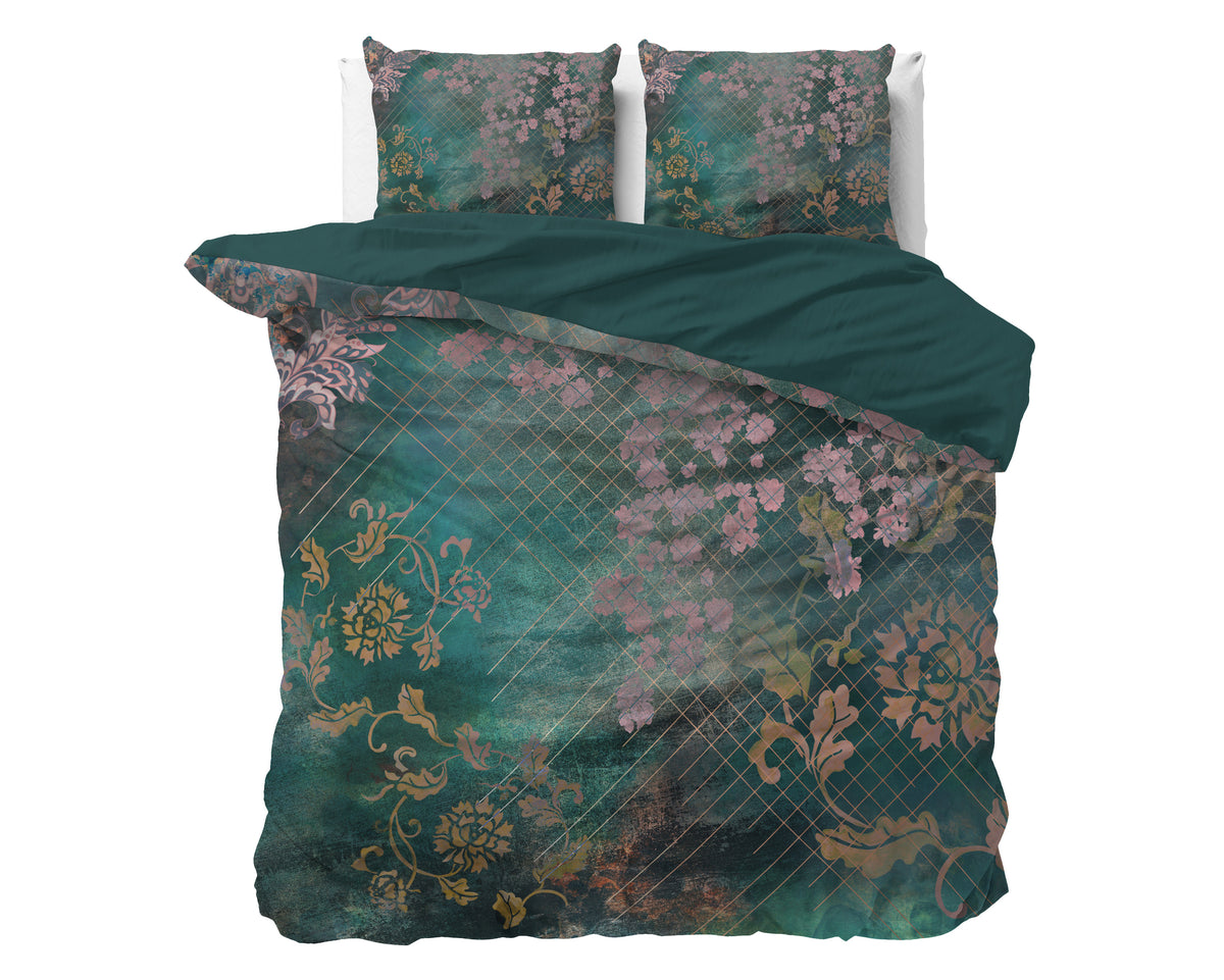 Groen dekbedovertrek met roze bloemen en goudkleurige ranken op een bed, met twee kussens en effen groene keerzijde