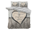 Grijs dekbedovertrek met hart, tekst To the moon and back en houtlook print, met twee kussens op een bed