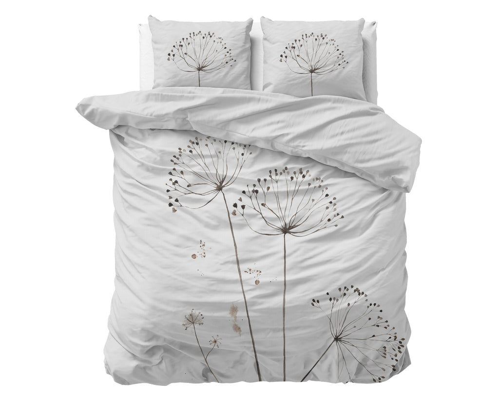 Wit dekbedovertrek met bloemenprint in taupe en bruin, met twee kussens op een bed