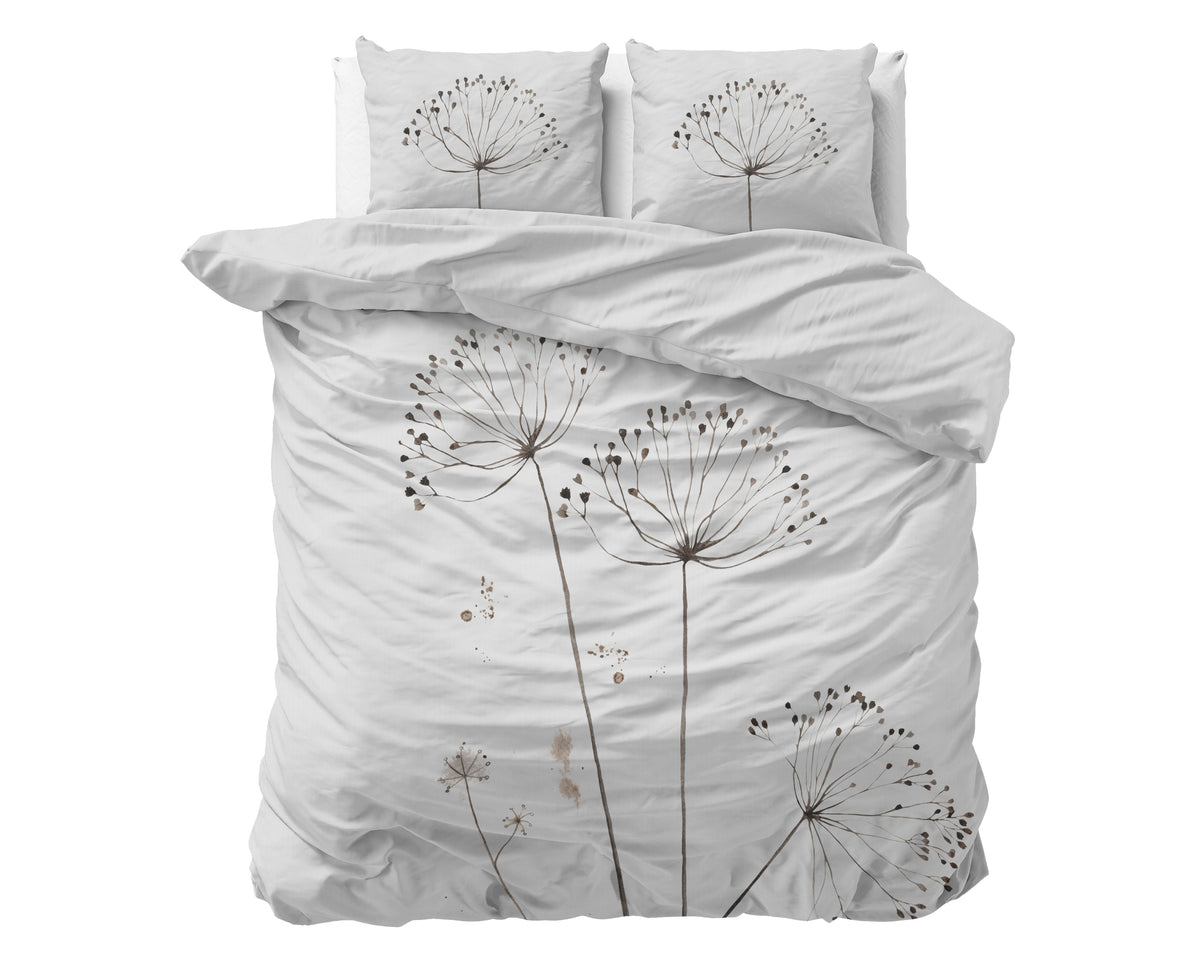 Wit dekbedovertrek met bloemenprint in taupe en bruin, met twee kussens op een bed