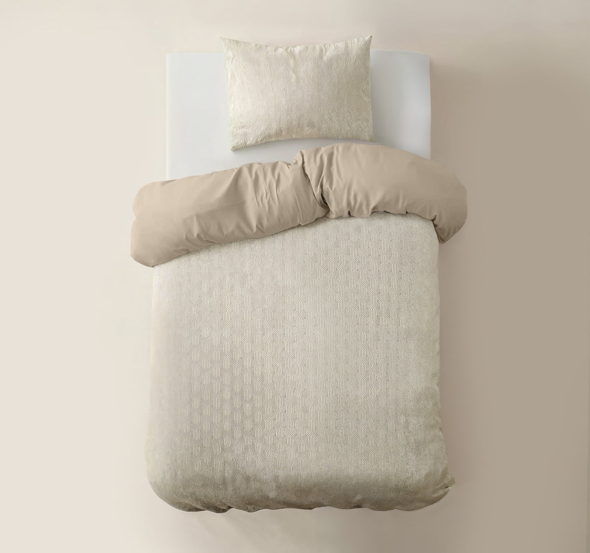 Beige dekbedovertrek met subtiel grafisch motief en zandkleurige achterzijde, met kussensloop op een bed, bovenaanzicht