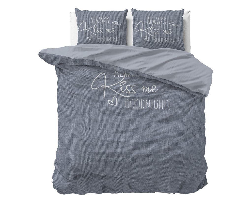 Blauwgrijs dekbedovertrek met lichte tekst Always Kiss me goodnight en twee kussenslopen met dezelfde print op een bed