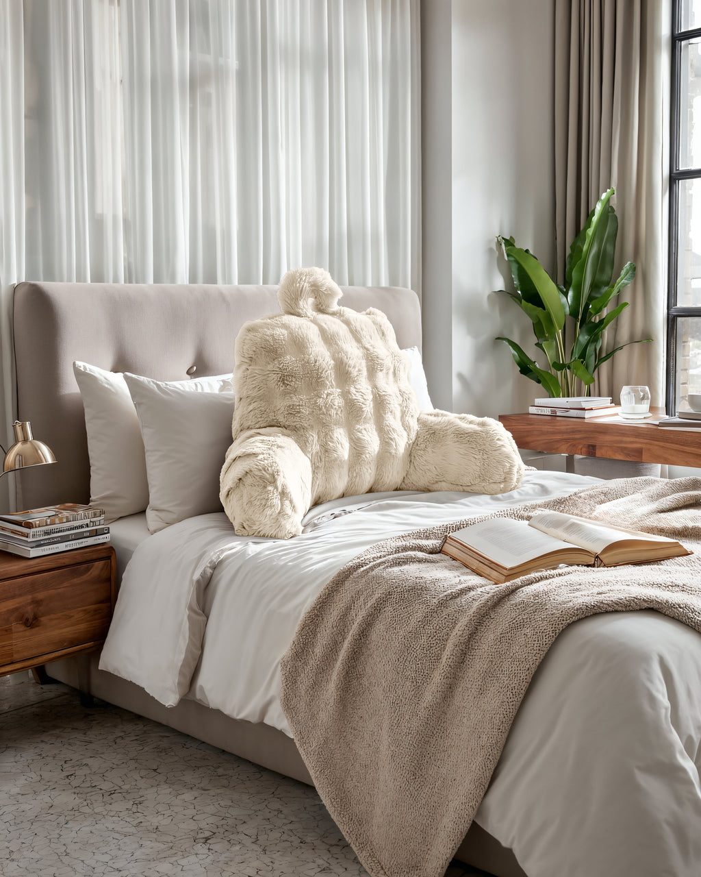Beige rugsteunkussen van nepbont met armleuningen op een bed met witte kussens en een taupe plaid
