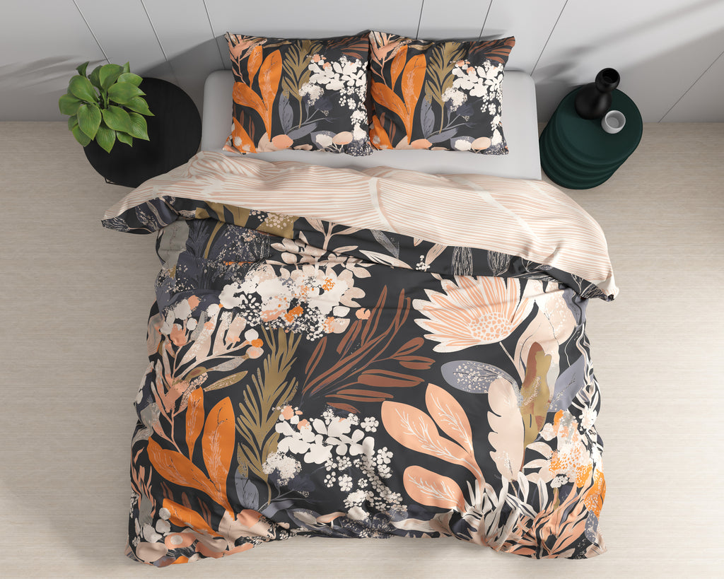 Zwart dekbedovertrek met oranje, perzik en crème bloemenprint en twee bijpassende kussenslopen op een bed, bovenaanzicht