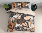 Bed met zwart dekbedovertrek met oranje en perzikkleurige bloemenprint, twee kussens en een streepmotief aan de achterkant