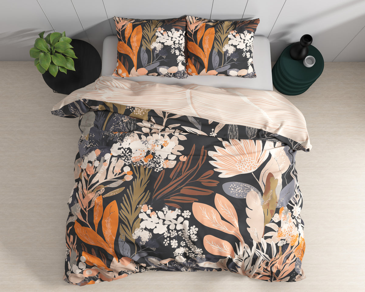 Bed met zwart dekbedovertrek met oranje en perzikkleurige bloemenprint, twee kussens en een streepmotief aan de achterkant