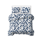 Opgemaakt bed met blauw-wit grafisch lazy dekbed en twee bijpassende kussens, gezien van boven