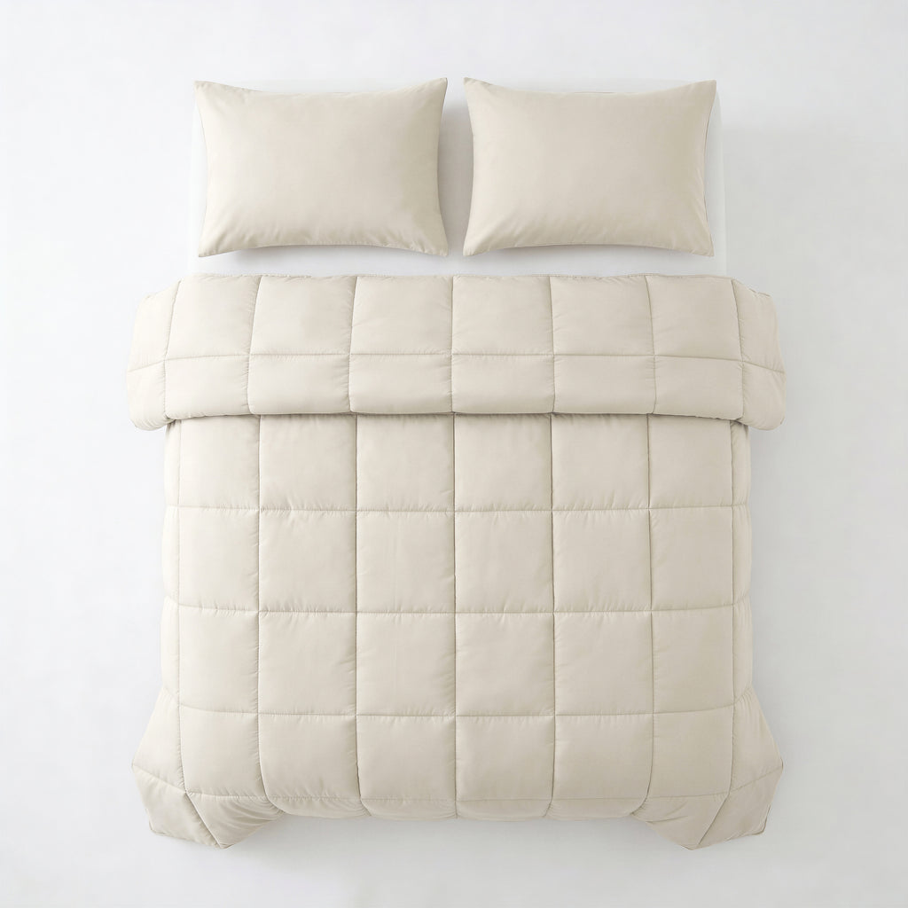 Beige lazy dekbed met vierkant stikpatroon en twee bijpassende kussens, van bovenaf gezien op een bed