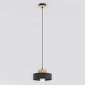 Zwarte hanglamp met houten detail aan zwart snoer en houten plafondplaat, met zichtbare lamp onder de kap