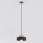 Zwarte hanglamp met houten detail aan zwart snoer en houten plafondplaat, met zichtbare lamp onder de kap