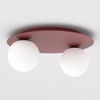 Bordeauxkleurige plafondlamp met ronde plaat en twee witte glazen bollen tegen een wit plafond