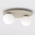 Beige plafondlamp met ronde plaat en twee matte witte glazen bollen tegen een lichte plafondondergrond