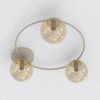 Plafondlamp met beige cirkelvormig frame en drie amberkleurige glazen bollen