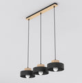 Zwarte hanglamp met drie ronde kappen en houten accenten aan een langwerpige houten plafondplaat
