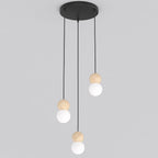 Hanglamp met drie hangende lichtpunten met houten bollen en witte kappen aan een ronde zwarte plafondplaat