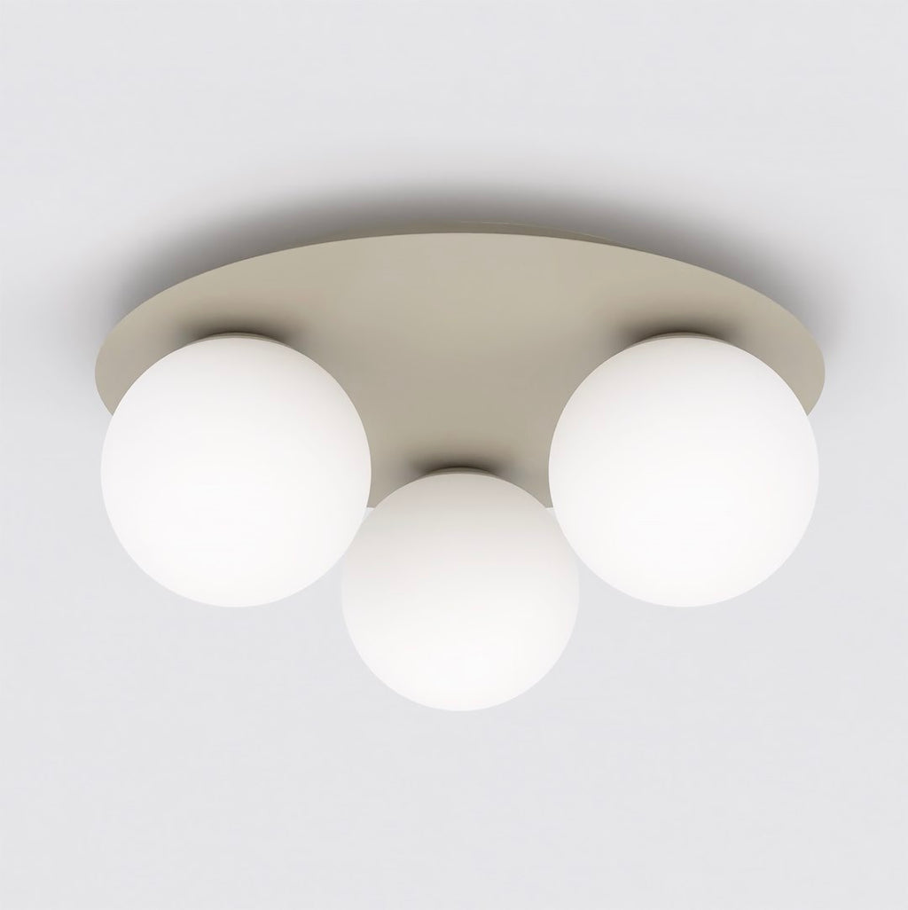 Beige ronde plafondlamp met drie matte witte glazen bollen tegen een wit plafond