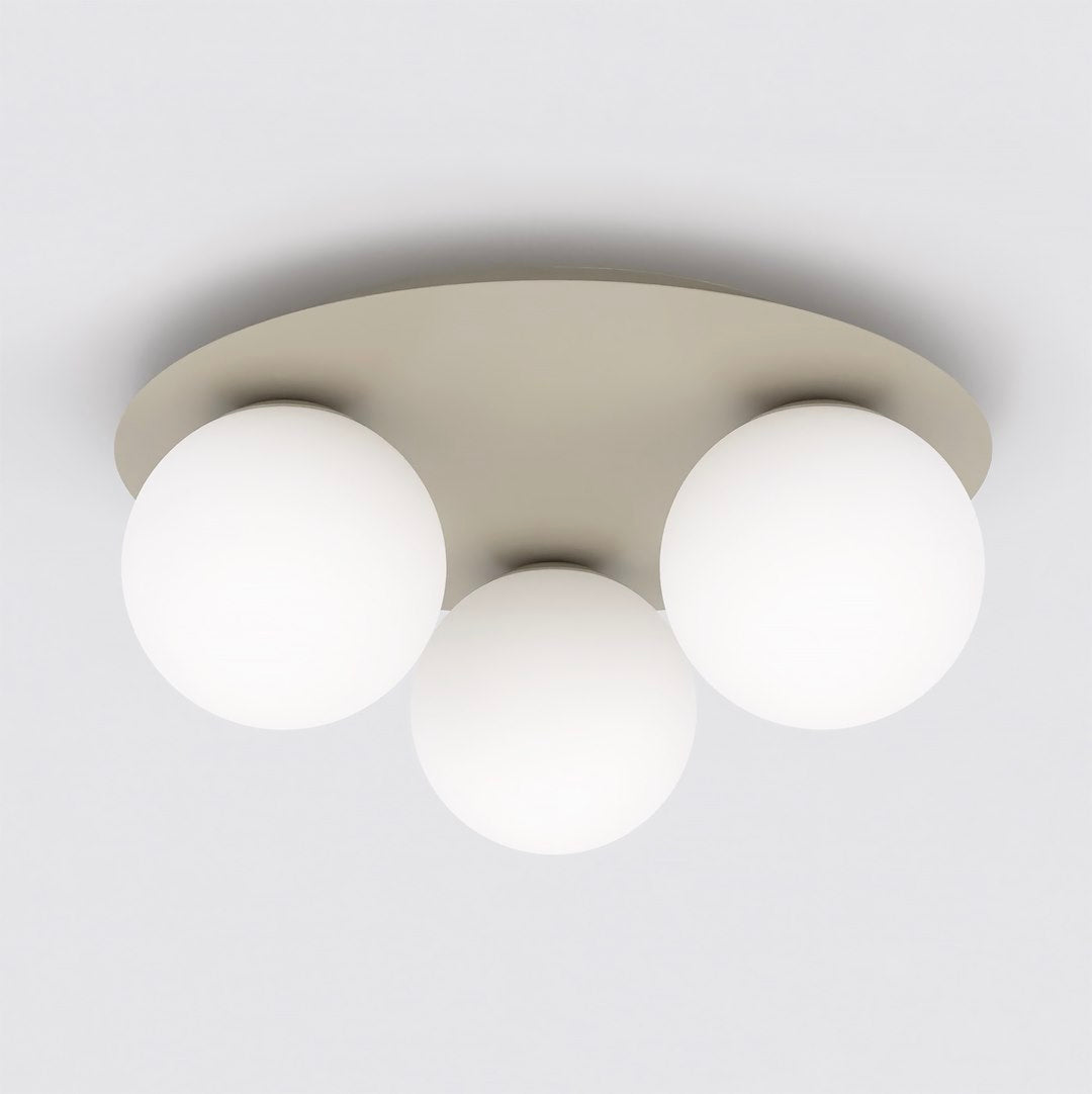 Beige ronde plafondlamp met drie matte witte glazen bollen tegen een wit plafond