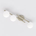 Beige plafondlamp met drie armen en drie witte glazen bollen, gezien van onderaf tegen een wit plafond