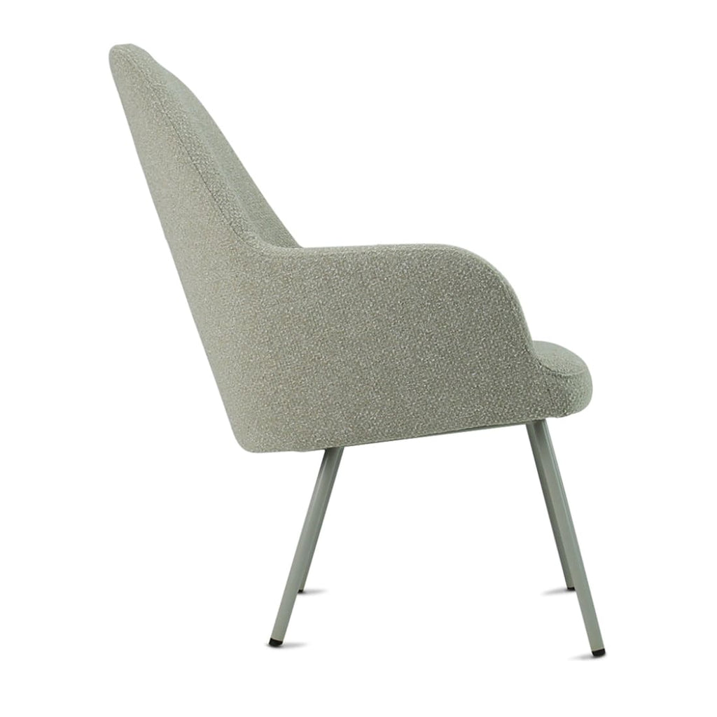Zijaanzicht van een saliegroene loungefauteuil met bouclé bekleding, ronde armleuning en vier slanke poten