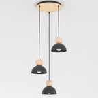 Hanglamp met drie zwarte stalen kappen en houten bollen aan een ronde houten plafondplaat